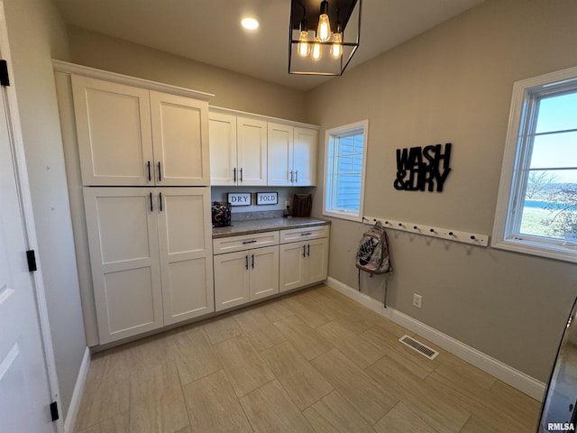 kitchen with a notable chandelier, hanging light fixtures, and white cabinets