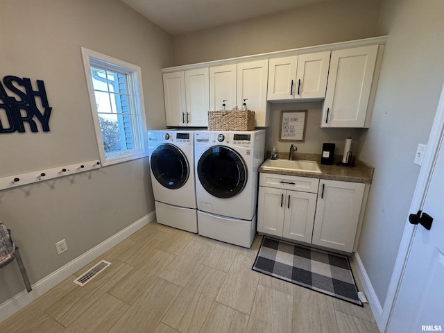 washroom with cabinets, sink, independent washer and dryer, and light hardwood / wood-style flooring