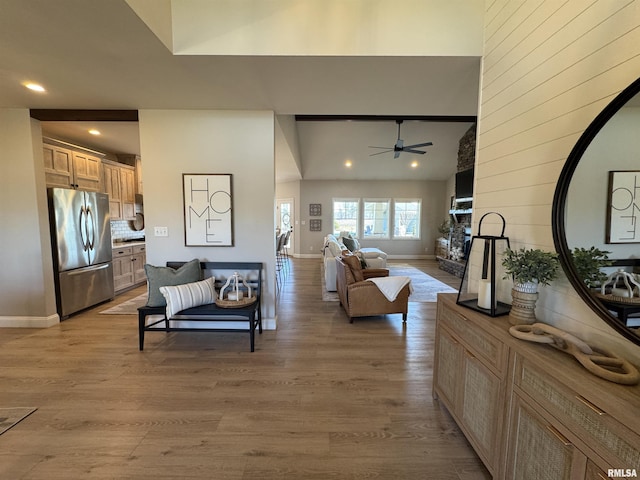 living room featuring light hardwood / wood-style flooring, ceiling fan, and a high ceiling