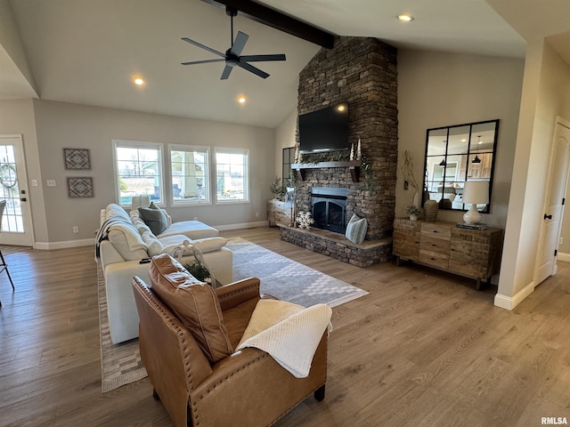 living room with a stone fireplace, high vaulted ceiling, light wood-type flooring, ceiling fan, and beam ceiling