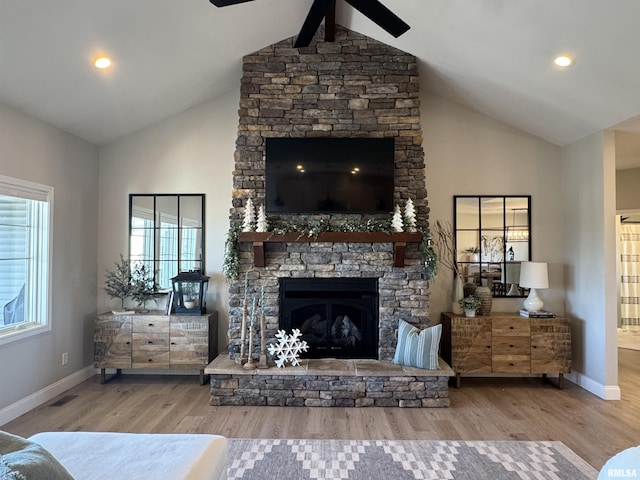 living room with high vaulted ceiling, a stone fireplace, hardwood / wood-style floors, and ceiling fan