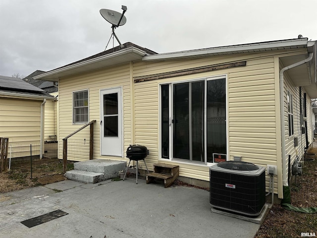 rear view of house with central AC unit and a patio