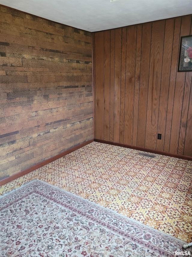 carpeted spare room featuring wood walls