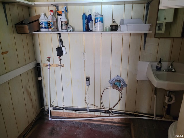 bathroom featuring wooden walls, concrete flooring, and sink