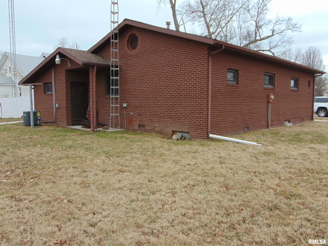 view of side of property with a yard and central AC