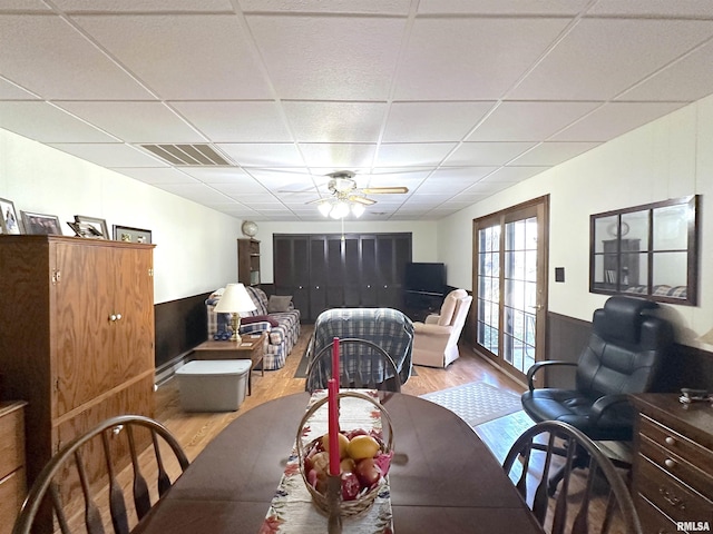 dining area with a paneled ceiling, ceiling fan, and light wood-type flooring