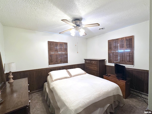 bedroom featuring wooden walls, carpet, and a textured ceiling