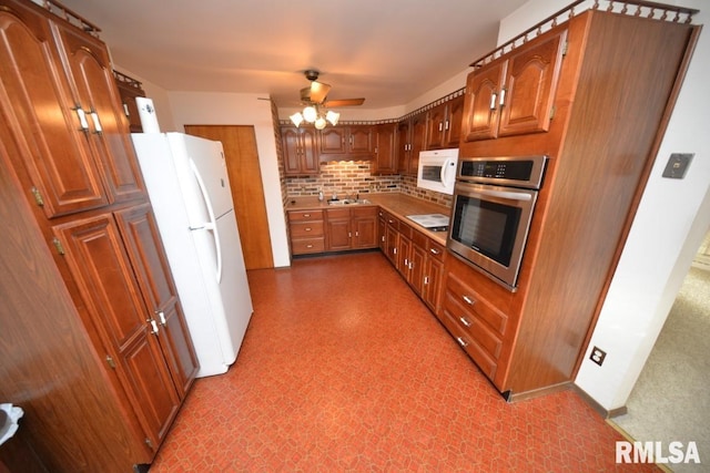 kitchen featuring tasteful backsplash, ceiling fan, sink, and white appliances