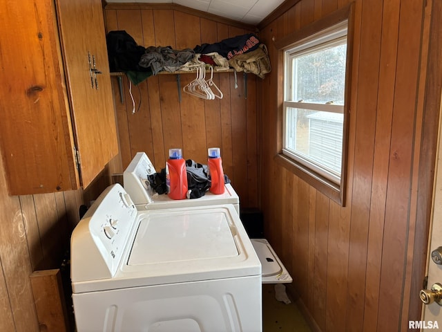 laundry room with washing machine and clothes dryer and wood walls