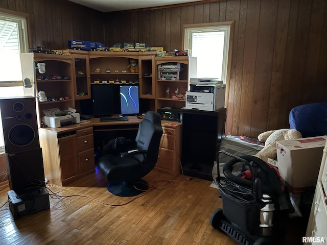 office with light hardwood / wood-style flooring, a healthy amount of sunlight, and wood walls