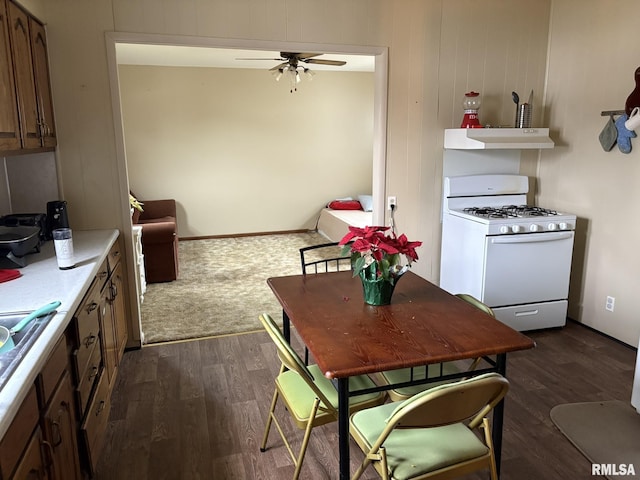 kitchen featuring dark wood-type flooring, white gas stove, and ceiling fan