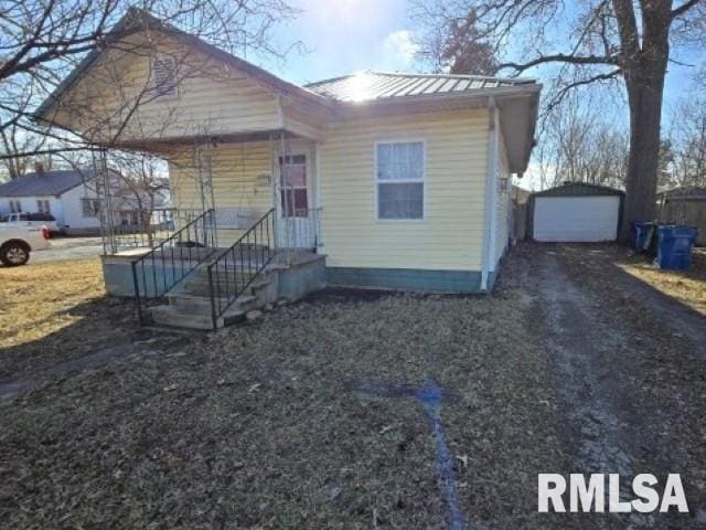 view of front of property featuring an outbuilding, metal roof, driveway, and a garage