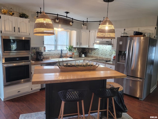 kitchen with wood counters, sink, appliances with stainless steel finishes, a kitchen island, and white cabinets