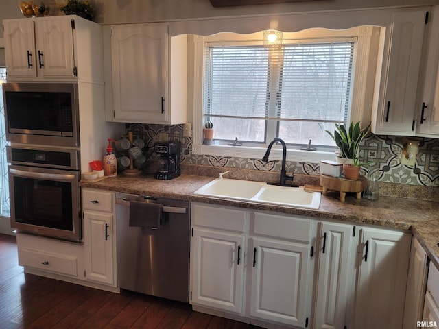 kitchen with dark hardwood / wood-style floors, white cabinetry, sink, decorative backsplash, and stainless steel appliances