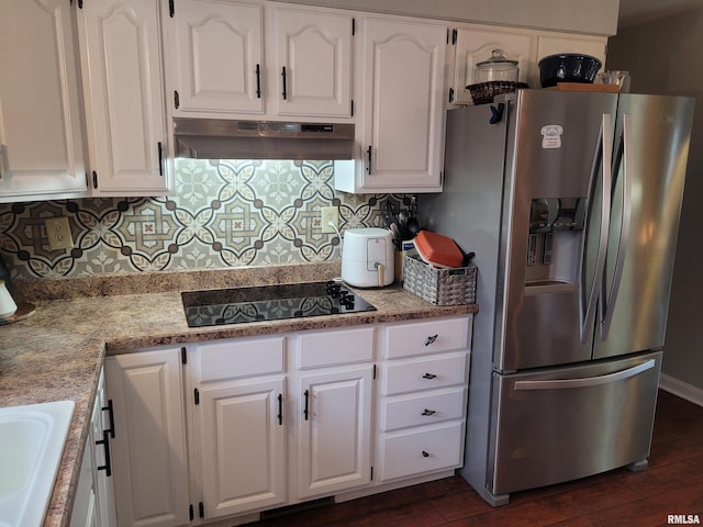 kitchen featuring stainless steel fridge, light stone counters, white cabinets, black electric cooktop, and decorative backsplash