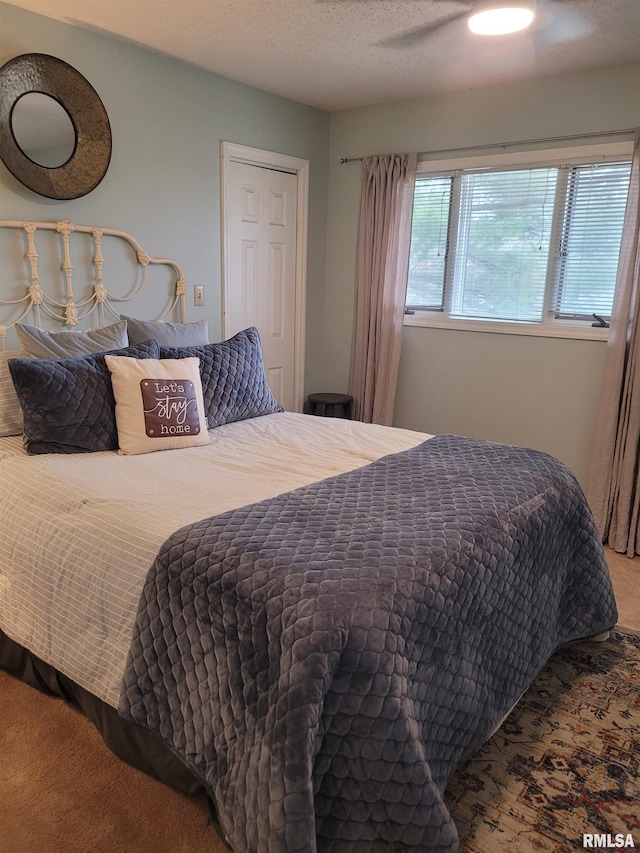 bedroom with ceiling fan, carpet floors, and a textured ceiling