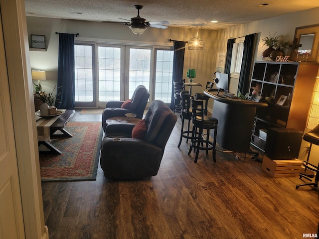 living room featuring ceiling fan, dark hardwood / wood-style floors, and a textured ceiling