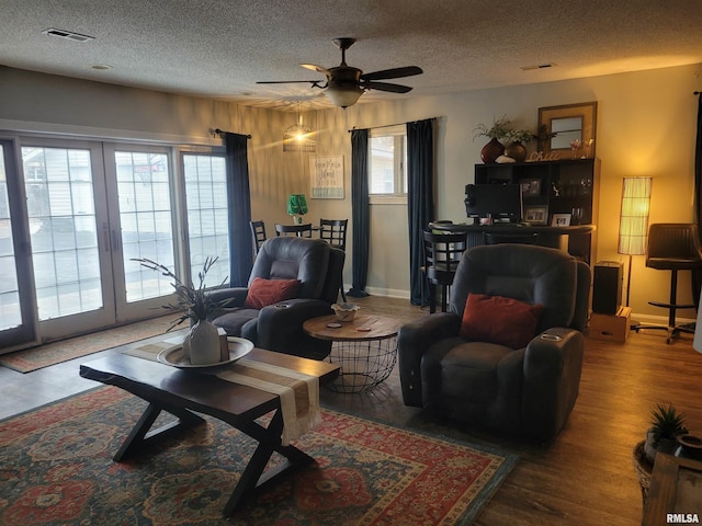 living room featuring ceiling fan, wood-type flooring, and a textured ceiling