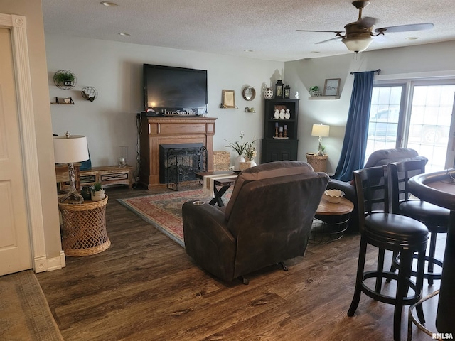 living room with ceiling fan, dark hardwood / wood-style flooring, and a textured ceiling