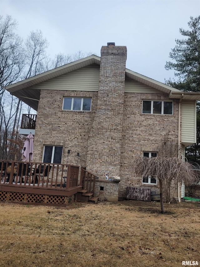 rear view of house featuring a wooden deck and a lawn