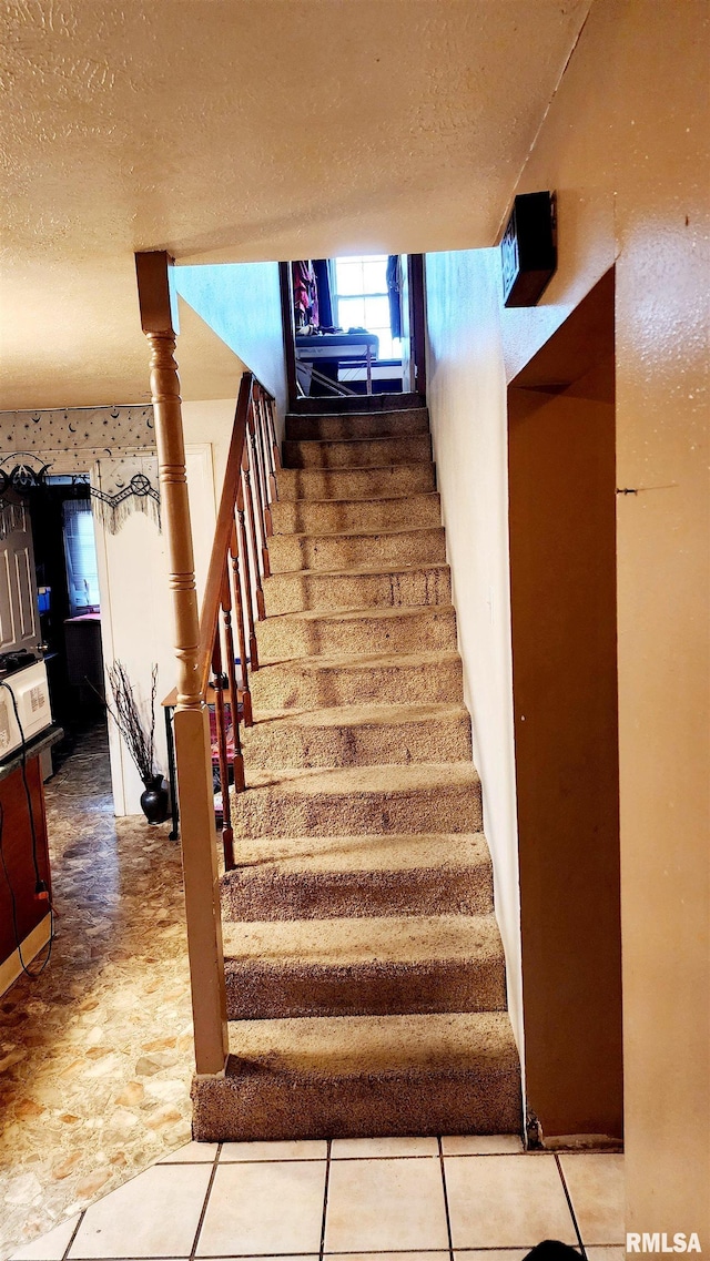 staircase featuring a textured ceiling