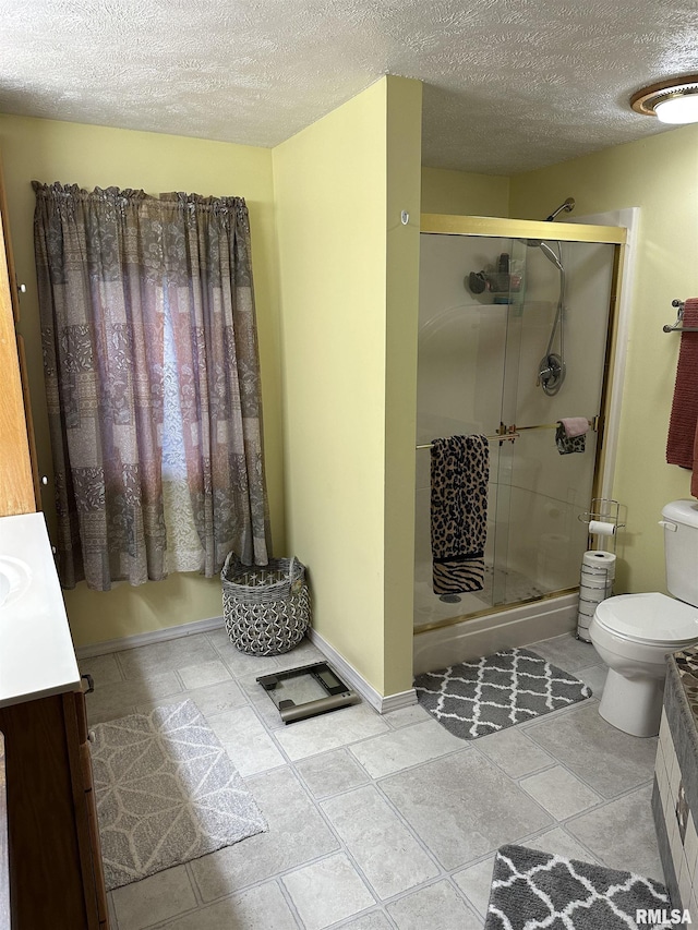 bathroom with vanity, a textured ceiling, a shower with shower door, and toilet