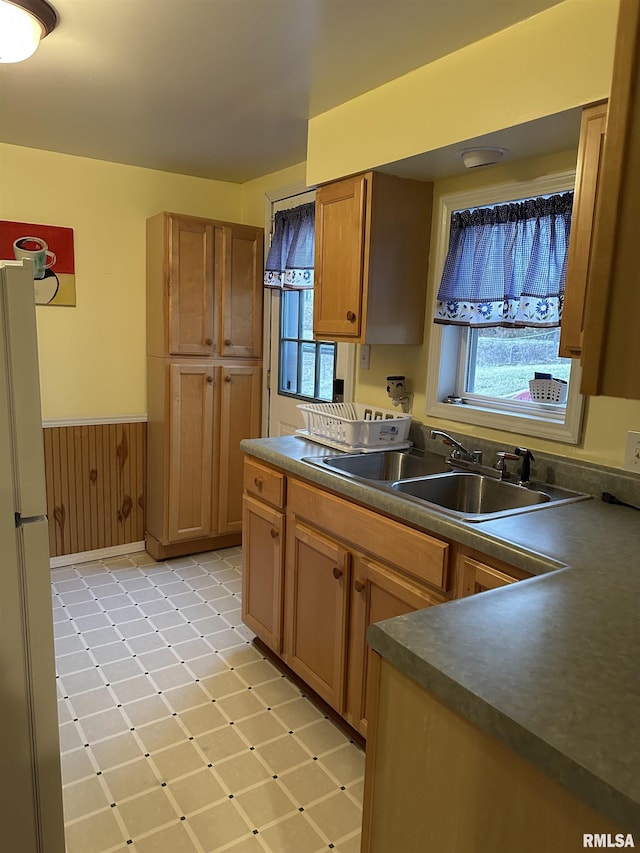 kitchen with refrigerator, sink, and wood walls