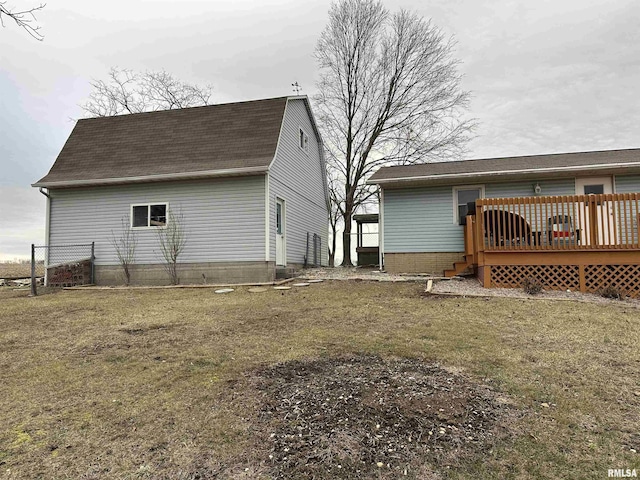 rear view of house with a wooden deck and a lawn