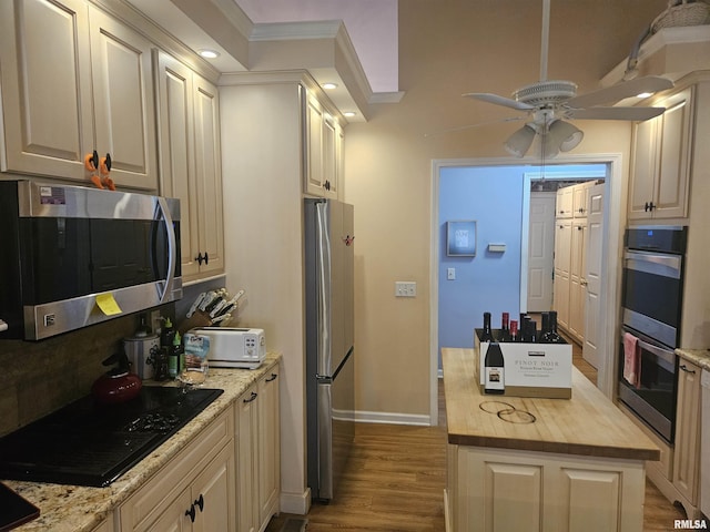 kitchen with appliances with stainless steel finishes, butcher block countertops, ornamental molding, ceiling fan, and light hardwood / wood-style flooring