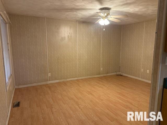 empty room with ceiling fan and light hardwood / wood-style floors