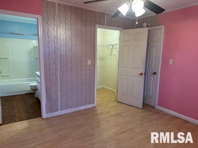 unfurnished bedroom featuring crown molding, ensuite bathroom, ceiling fan, and light hardwood / wood-style floors