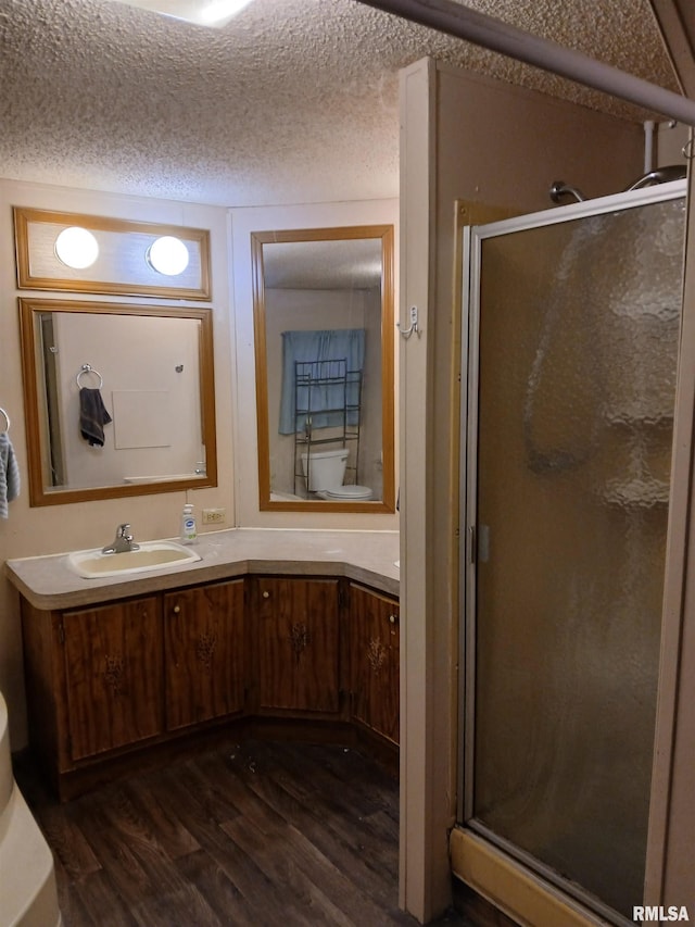 520 Dewey St, Eldorado, IL 62930 - bathroom with a textured ceiling, wood finished floors, a stall shower, and vanity