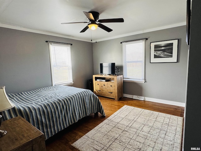 bedroom featuring multiple windows, ornamental molding, dark wood-type flooring, and ceiling fan