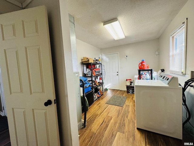 clothes washing area featuring washing machine and clothes dryer, a textured ceiling, and light wood-type flooring