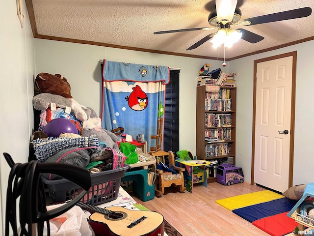 playroom featuring ceiling fan, ornamental molding, hardwood / wood-style floors, and a textured ceiling