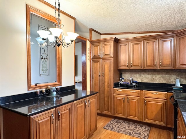 kitchen with a textured ceiling, a notable chandelier, light hardwood / wood-style floors, and decorative light fixtures