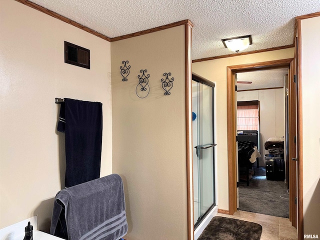 bathroom featuring walk in shower, crown molding, and a textured ceiling