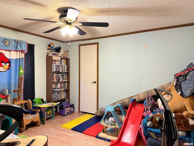 game room with ceiling fan, ornamental molding, light hardwood / wood-style floors, and a textured ceiling