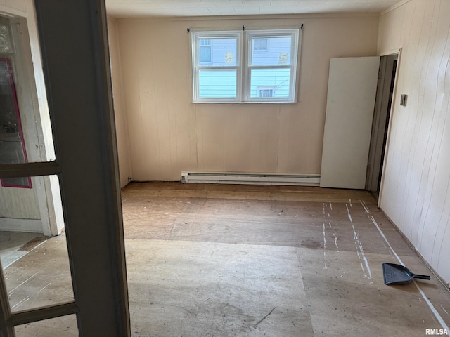 empty room with a baseboard heating unit, hardwood / wood-style flooring, and wooden walls