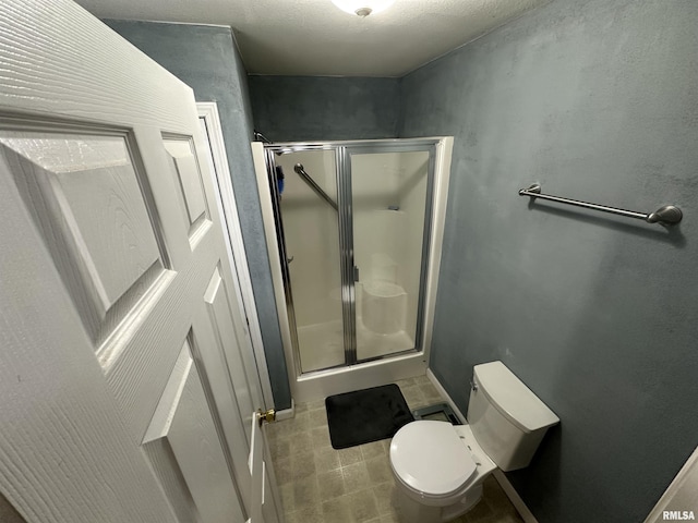 bathroom featuring a shower with shower door and toilet