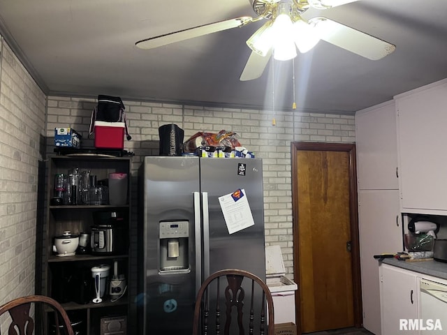 kitchen with ceiling fan, dishwasher, white cabinetry, brick wall, and stainless steel fridge with ice dispenser