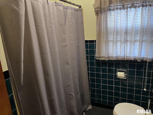 bathroom with toilet and tile walls