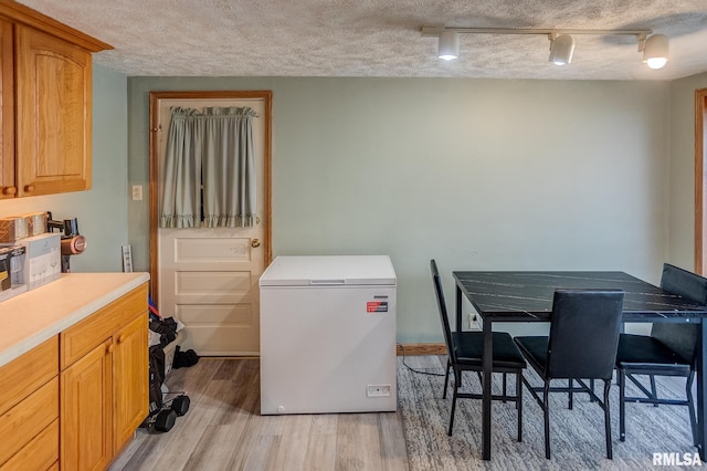 interior space featuring track lighting, a textured ceiling, and light wood-type flooring