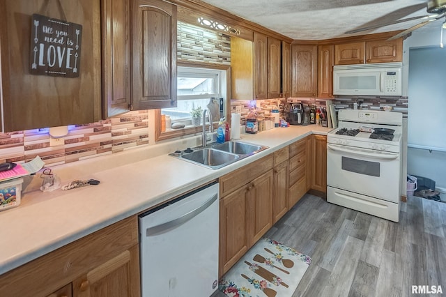 kitchen with sink, white appliances, ceiling fan, tasteful backsplash, and wood-type flooring