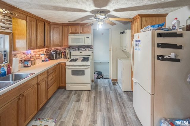 kitchen featuring white appliances, ceiling fan, stacked washing maching and dryer, light hardwood / wood-style floors, and decorative backsplash