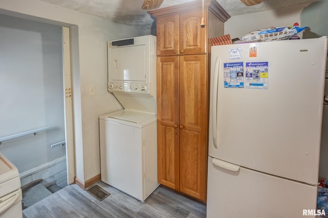 laundry room with stacked washer and clothes dryer and light wood-type flooring