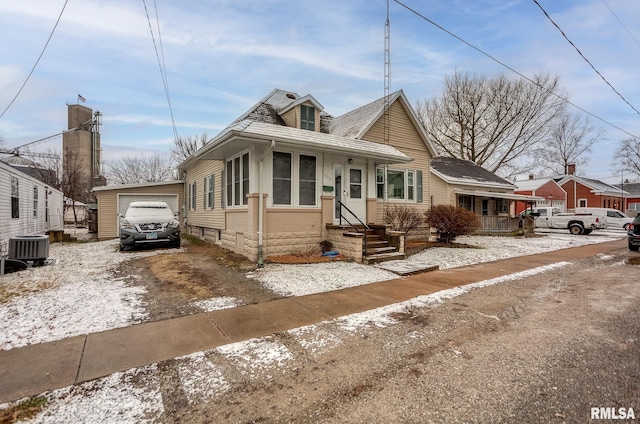 bungalow-style home with central AC unit and a garage