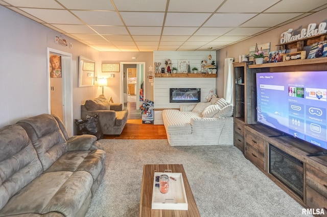 carpeted living room featuring a drop ceiling