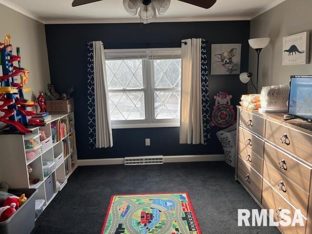 rec room with crown molding, ceiling fan, and dark carpet