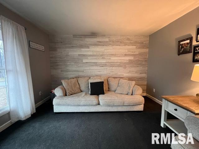 interior space with dark carpet, wooden walls, and plenty of natural light